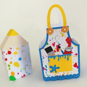 May include: A white paper pencil-shaped box and a paper apron-shaped container. Both are decorated with colorful paint splatters. The apron has a yellow pocket and handle, and contains art supplies. The pencil box has a yellow tip.