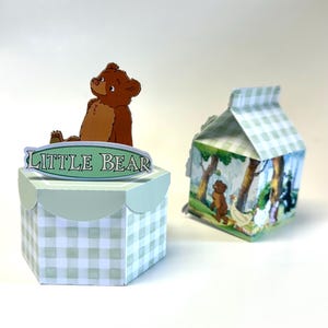 May include: Two decorative boxes. One is a hexagonal box with a light green and white gingham pattern, topped with a brown bear figure and a sign that reads "LITTLE BEAR". The other is a milk carton-shaped box with a forest scene.