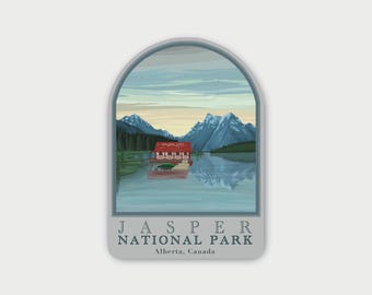 May include: An arched sticker featuring a landscape illustration of a red boathouse on a lake with snow-capped mountains in the background. The text reads JASPER NATIONAL PARK Alberta, Canada in a dark grey serif font at the bottom of the design.