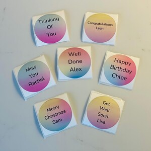 Puede incluir: Ocho pegatinas cuadradas de colores con esquinas redondeadas y fondo blanco. Cada pegatina tiene un mensaje y un nombre diferentes, como "Thinking of You", "Congratulations Leah", "Miss You Rachel", "Well Done Alex", "Happy Birthday Chloe", "Merry Christmas Sam", "Get Well Soon Lisa".