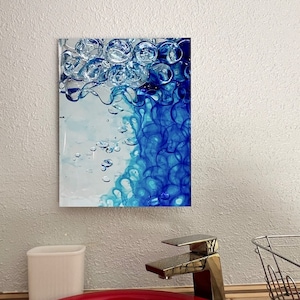 Könnte beinhalten: Abstrakter Kunstdruck mit einem blauen und weißen Design mit wirbelnden Formen und Blasen. Der Druck ist gerahmt und hängt an einer weißen Wand.