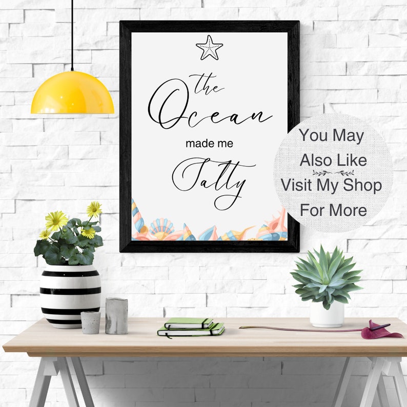 May include: A framed print with the text "The Ocean made me Salty" in black cursive font. A starfish and seashells are depicted in the bottom corner. The print is on a white background and has a black frame. The text "You May Also Like Visit My Shop For More" is on a white background with a gray linen texture.