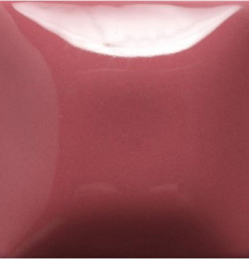 Puede incluir: Un cuadrado liso y s&oacute;lido de pigmento rosa polvoriento con un acabado brillante y reflectante. La superficie muestra una saturaci&oacute;n de color opaca y uniforme con un reflejo de luz blanco brillante en el borde superior.