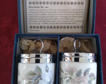 Royal Worcester Set vintage di due coddler per uova in porcellana con un grazioso design a rose, uno con rose rosa e l'altro blu nella scatola originale.