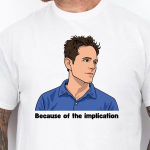 May include: White t-shirt featuring a cartoon illustration of a man in a blue shirt, with the text "Because of the implication" in black font. The shirt is a casual style.