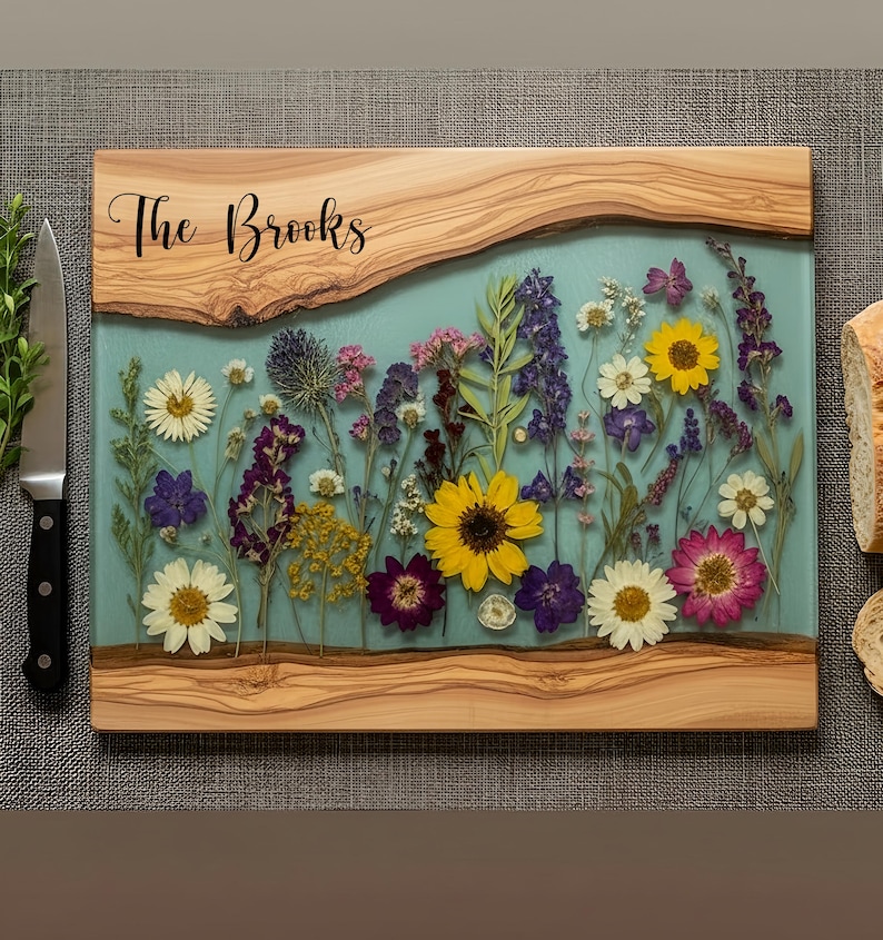 A glass and wood cutting board with pressed flowers inside