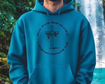 May include: Teal hoodie with a front pocket and drawstring hood. The front features a circular graphic with a cross, ribbons, and the text "ALL FOR HIS GLORY" and "1 CORINTHIANS 15:58". The hoodie is a solid teal color.