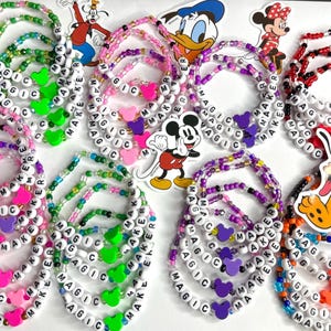 May include: A collection of colorful beaded bracelets with the words "MAGIC MAKER" spelled out on each one. The bracelets are decorated with small plastic Mickey Mouse ears in various colors.