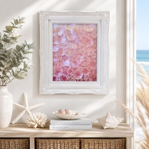 Op de afbeelding: Een rechthoekig wandkunstwerk met een roze en iriserend bellenpatroon, gevat in een sierlijke witte lijst. Het kunstwerk toont talloze overlappende cirkelvormige figuren in verschillende zachte roze tinten, wat een gestructureerd en lichtreflecterend effect creëert.