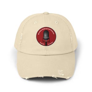 May include: A beige distressed baseball cap with a red circle logo featuring a microphone and the text "Brewery Underground Podcast Nashville Tennessee".