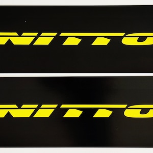 May include: Two black rectangular stickers with the word "NITTO" in yellow lettering.