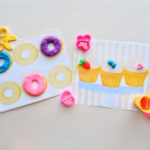 May include: A set of play dough tools and molds for making donuts and cupcakes. The tools include a pair of scissors, a heart-shaped mold, a butterfly mold, and a container of play dough. The molds are used to create donuts and cupcakes with different colors and designs.
