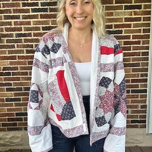 May include: A white quilted jacket with red, blue, and white patchwork design. The jacket has a relaxed fit and long sleeves.