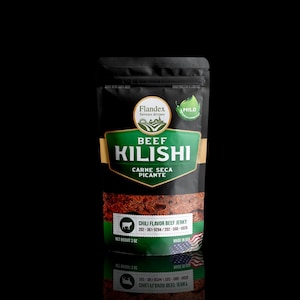 May include: A black resealable bag of beef jerky with a green and gold label. The label reads "Beef Kilishi Carne Seca Picante" and "Chili Flavor Beef Jerky". The bag is on a black surface.