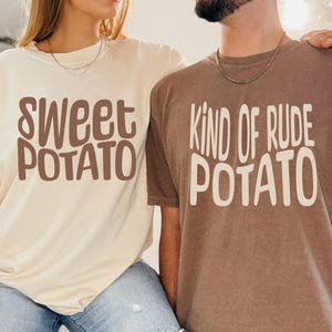 May include: Two people wearing matching t-shirts. One shirt is ivory and says "Sweet Potato" in brown letters. The other shirt is espresso and says "Kind of Rude Potato" in white letters. Both shirts are short-sleeved.
