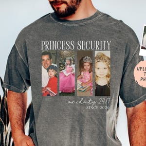 Może przedstawiać: Szara koszulka z nadrukiem "PRINCESS SECURITY" i "on duty 24/7 SINCE 2020" z przodu. Koszulka posiada cztery panele ze zdjęciami dziecka. Dołączone jest małe zdjęcie z tekstem "UPLOAD UP TO 4 PHOTOS".