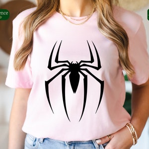 Puede incluir: Una camiseta rosa con un logotipo de Spiderman negro impreso en la parte delantera.