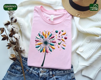 May include: Pink t-shirt with a graphic of a dandelion made of bowling pins and balls. The dandelion is blowing in the wind.