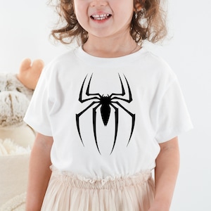 Puede incluir: Camiseta blanca con un gr&aacute;fico de ara&ntilde;a negra en la parte delantera.