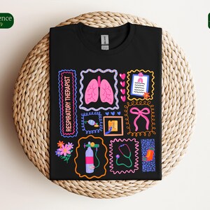 May include: Black t-shirt featuring colorful illustrations related to respiratory therapy. The design includes images of lungs, a stethoscope, flowers, and the text "RESPIRATORY THERAPIST" in a neon-style font. The shirt is displayed on a woven surface.