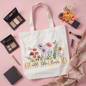 May include: A white tote bag with a floral design and the text "GOD all the time" in gold. The bag is surrounded by makeup products, including eyeshadow palettes, brushes, and a free cosmetic pouch.