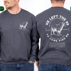 May include: A dark gray sweatshirt with a white graphic on the back. The graphic features a sheep and the text "He left the 99... to come find me."  The text also includes a Bible verse from Luke 15:3-7. The front of the sweatshirt has a small white sheep graphic.