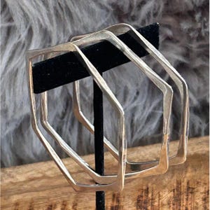 May include: A set of three ceramic mugs with a speckled, matte finish. The mugs are in shades of cream, light gray, and dark gray. Each mug has a simple, minimalist design and a rounded handle. The mugs are suitable for coffee, tea, or other beverages.