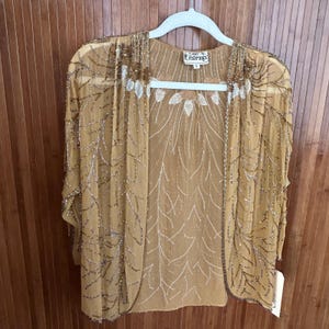 May include: A sheer mustard yellow open-front cardigan featuring intricate gold and silver beadwork in a leaf-like pattern. The garment has a round neckline, three-quarter length sleeves, and a label reading Sister Max with size S.