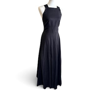 May include: A black, floor-length dress with a square neckline and wide straps. The dress is displayed on a white mannequin against a white background. The dress has a fitted bodice and a flowing skirt.
