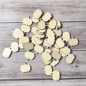 May include: A collection of small, unfinished wooden pumpkin cutouts. The pumpkins vary in shape and size, with some featuring a classic pumpkin silhouette and others with a more abstract design. Ideal for fall crafts and decorations.