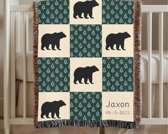 May include: A woven blanket with a forest theme. The blanket features a repeating pattern of black bears and evergreen trees on a cream and dark green background. The name "Jaxon" and the date "05-15-2025" are printed on the blanket.