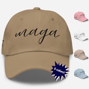 May include: A tan baseball cap with the word "maga" written in black cursive script. The cap is available in five colors.