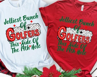 Może przedstawiać: Dwie koszulki z świątecznym wzorem golfowym. Biała koszulka ma czerwony i zielony napis "Jolliest Bunch of Golfers This Side of the 19th Hole". Czerwona koszulka ma ten sam wzór, ale z białym napisem.
