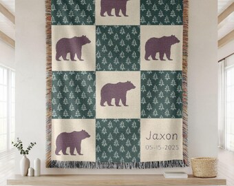 May include: A woven throw blanket with a patchwork design featuring alternating squares of dark green tree patterns and cream-colored squares with purple bear silhouettes. The name "Jaxon" and date "05-15-2025" are printed on one square. The blanket has a fringed edge.