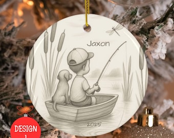May include: Round ceramic Christmas ornament with a pencil sketch of a boy fishing with a dog in a boat. The name "Jaxon" is above the boy, and the year "2025" is below. The ornament has a gold string for hanging.