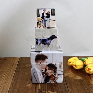 May include: Three personalized photo cubes stacked on a wooden surface. The cubes display images of a couple, a dog, and another couple. Yellow tulips are in the background.