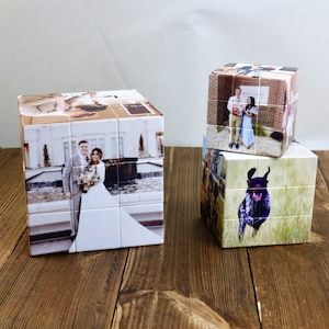 May include: Three personalized photo puzzle cubes. One cube features a wedding photo, while the other two display different images. The cubes are on a wooden surface, with a light-colored background.