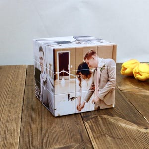 May include: A personalized photo cube featuring images of a wedding couple. The cube is made of multiple square blocks, each displaying a portion of a photograph. The images show the couple in formal attire, with a light background.