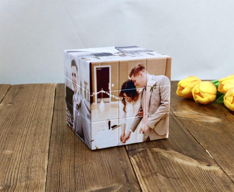 May include: A personalized photo cube featuring images of a wedding couple. The cube is made of multiple square blocks, each displaying a portion of a photograph. The images show the couple in formal attire, with a light background.