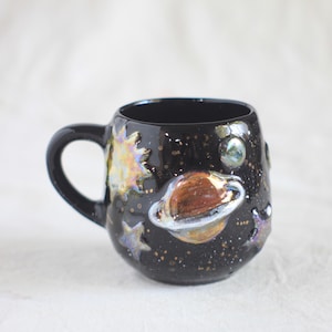Handgefertigter schwarzer Keramikbecher mit Planetenmotiven, mit Reliefdarstellung und schillernden Farben, Sonnensystem