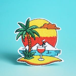 Può includere: Toppa ricamata raffigurante una scena di isola tropicale. Un tramonto giallo e arancione fa da sfondo a una palma, un cocktail e una piccola isola. La toppa ha un bordo bianco ed è ambientata su uno sfondo blu.