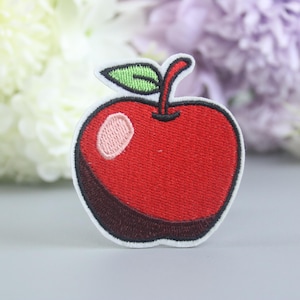 Pode incluir: Etiqueta bordada vermelha em forma de maçã com um caule e uma folha verdes, para passar a ferro.