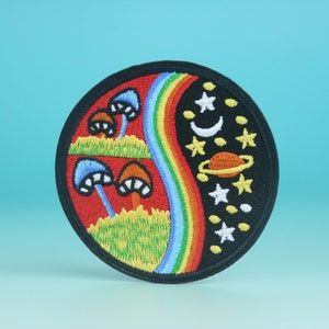 May include: A round embroidered patch with a yin yang design. One side features a rainbow and mushrooms, the other side features stars and a planet.