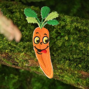 May include: An embroidered patch featuring a smiling orange carrot with green leafy tops.