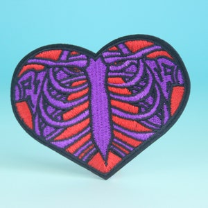May include: Purple and red embroidered iron-on patch shaped like a heart with a ribcage design inside.