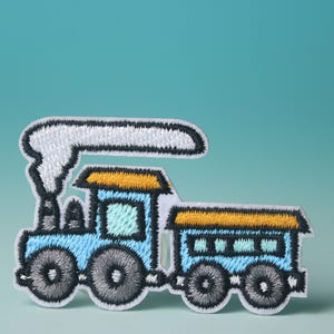 May include: Embroidered patch of a blue toy train with a yellow roof and white smoke. The train has black wheels and a white outline. The background is a solid teal colour.