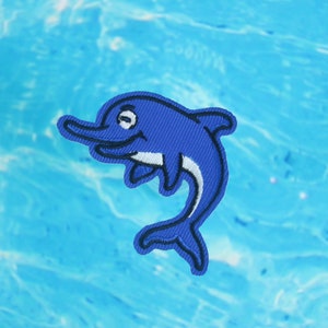 May include: A blue embroidered dolphin patch with a white belly, perfect for adding a playful touch to clothing or accessories.