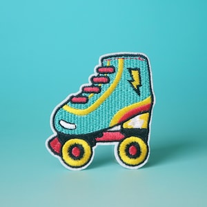 Op de afbeelding: Een turquoise en gele rol skate met rode accenten en een bliksemontwerp. De skate is geborduurd op een witte stoffen patch.