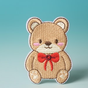 Può includere: Un orsacchiotto di peluche marrone ricamato con un fiocco rosso. L'orso è seduto con le zampe davanti a sé. Lo sfondo è azzurro chiaro.