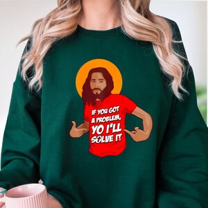 A person wearing a green sweatshirt with a graphic of a man with a beard and a red shirt with the text "If you got a problem, you'll solve it" printed on it.